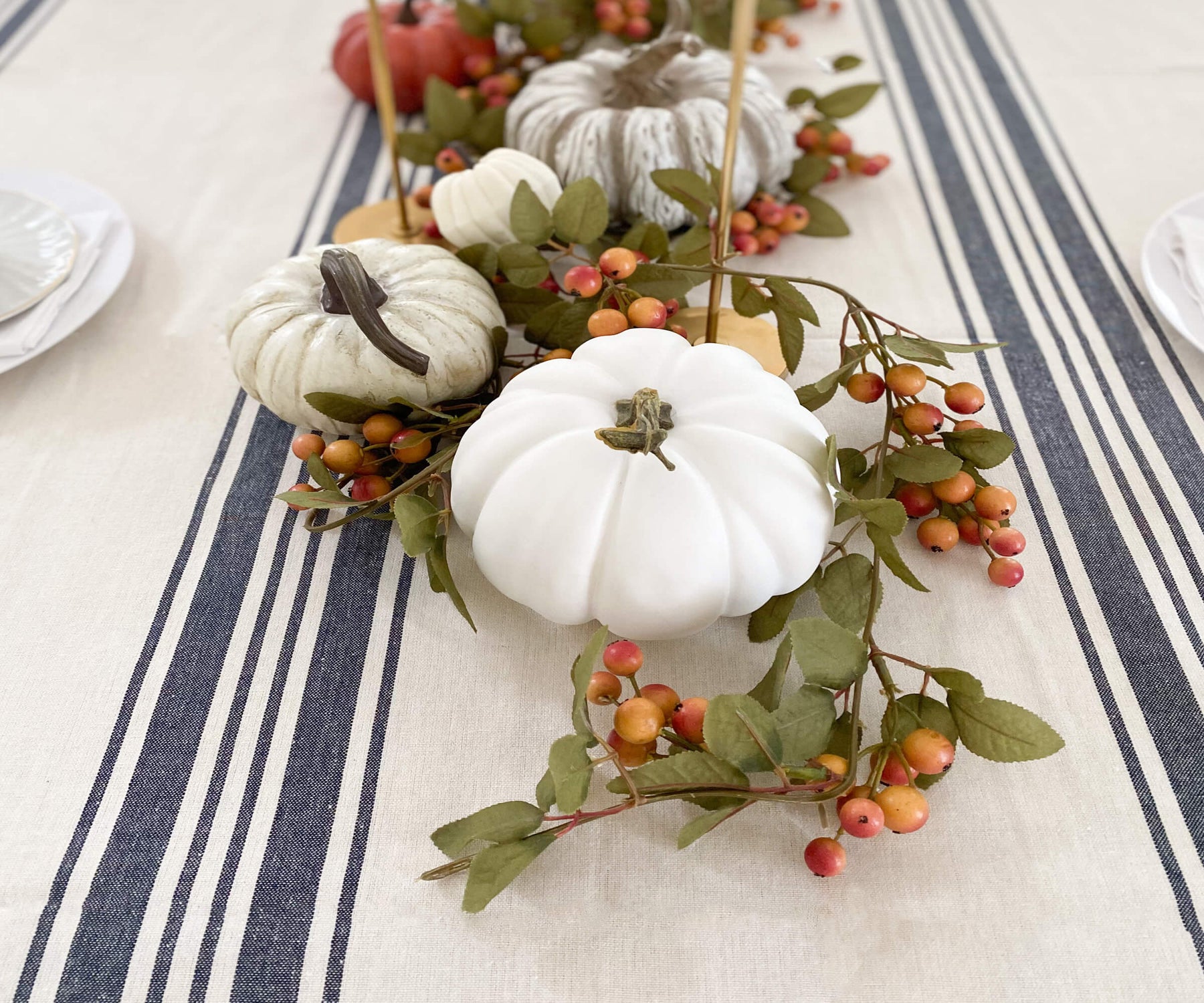 blue tablecloth table decorated with white pumpkins and berries on top of Farmhouse tablecloth