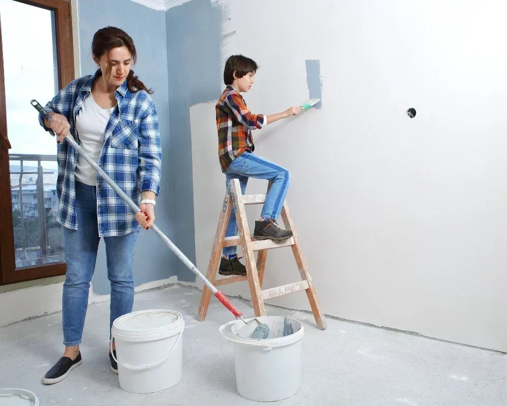 Woman and child painting a bedroom together, using buckets and a ladder.