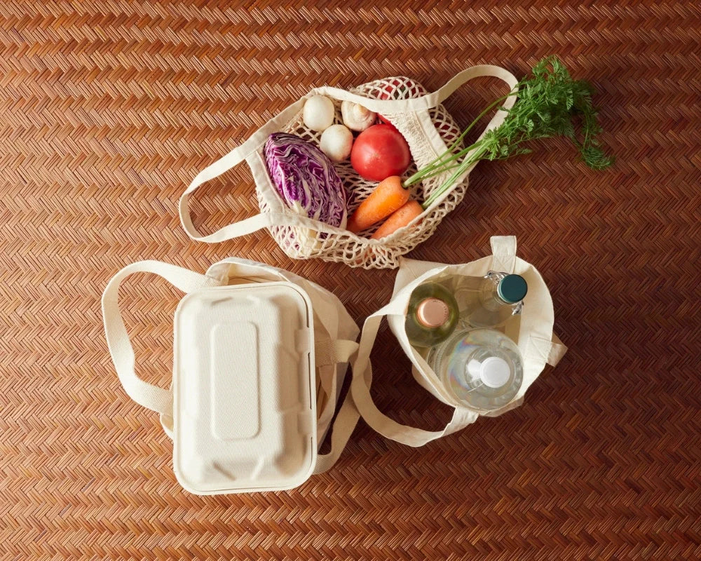 Mesh produce shopping bag with groceries on a woven surface
