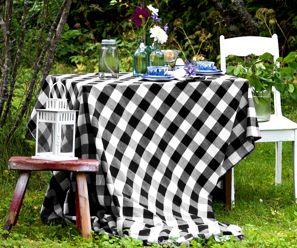  rectangle table covered with a black and white checkered tablecloth, specifically styled for a blog. The setting is designed to project a chic and contemporary look. 
