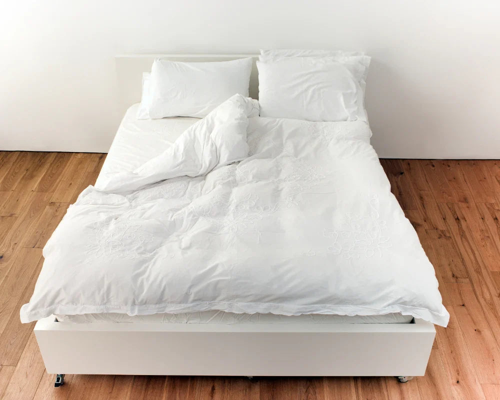 Fluffy white comforter neatly spread on a cozy bed with soft pillows, creating a warm and inviting bedroom setup.