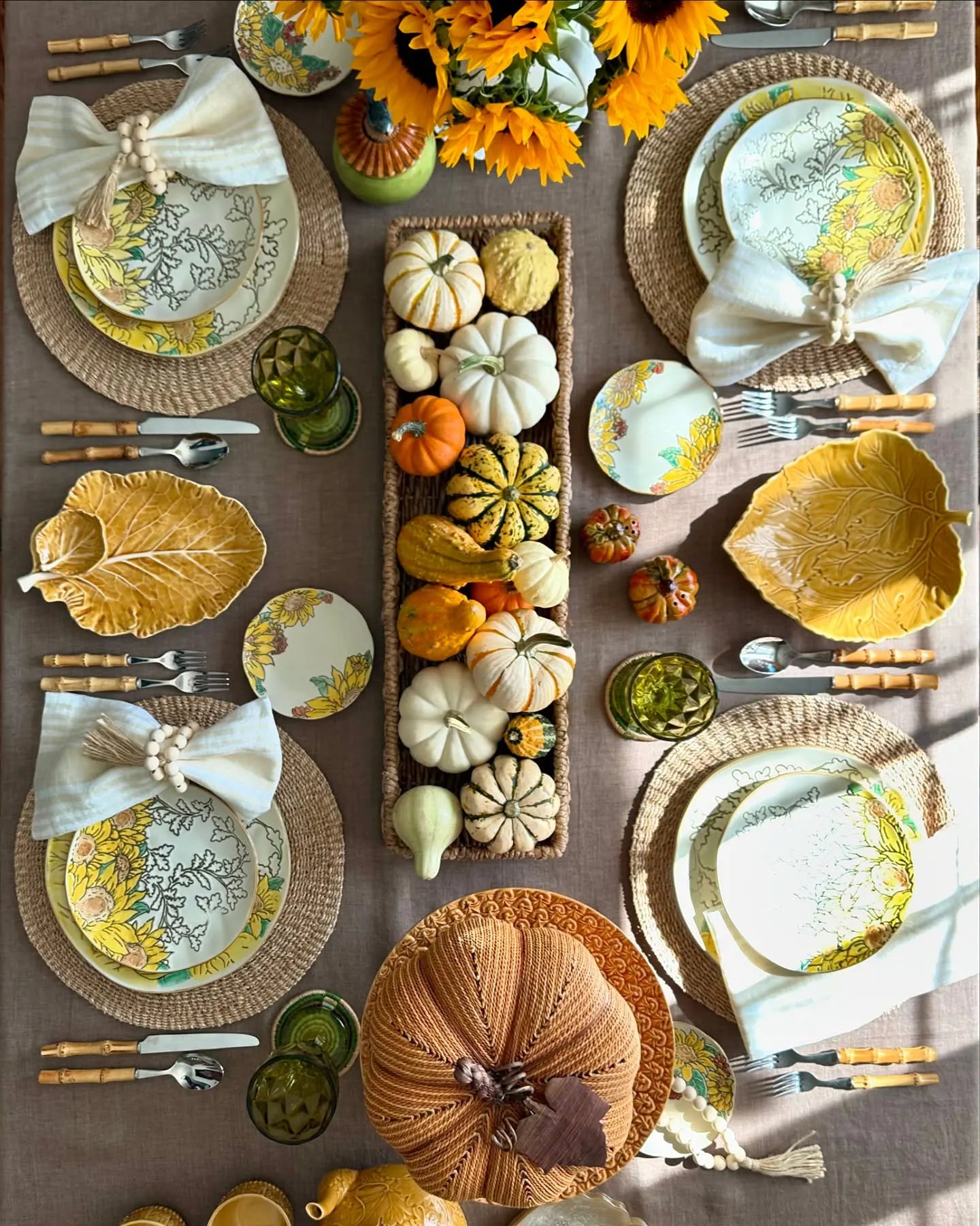 Fall table decor with pumpkins, sunflower centerpiece, leaf plates, and linen napkins