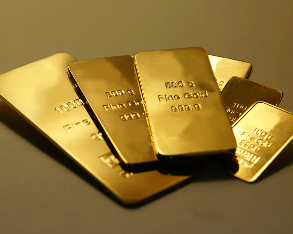 Gold bars with visible weight and purity markings on a dark background