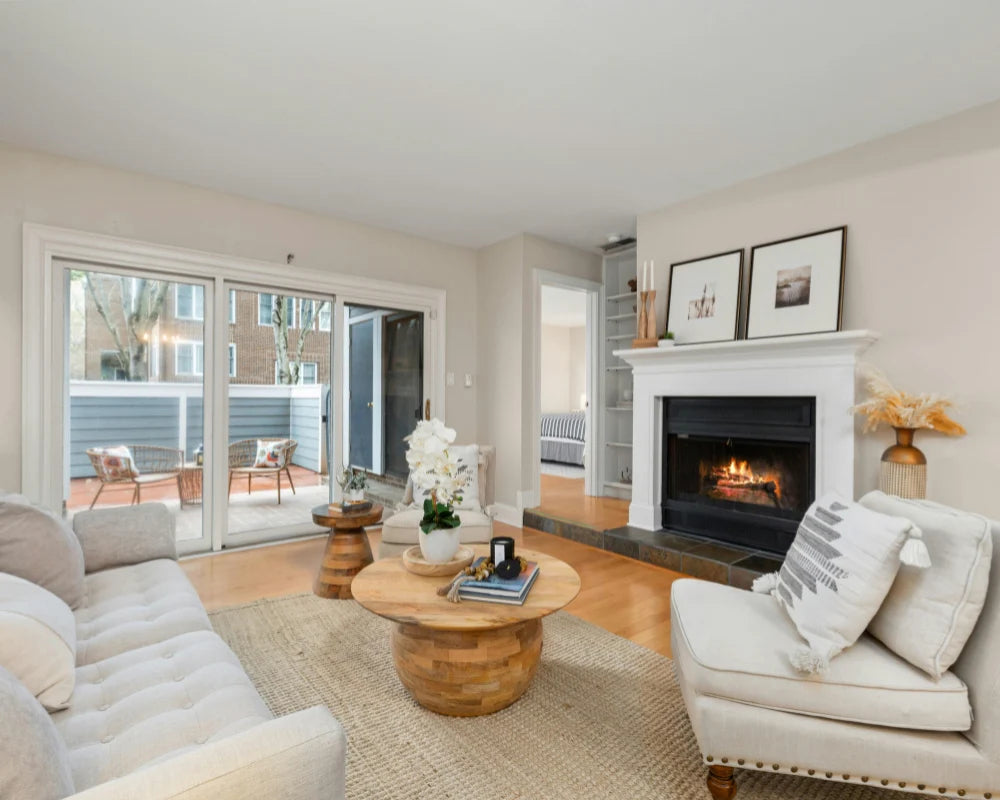 Warm and inviting renter-friendly living room with neutral decor, fireplace, cream sofa, woven rug, and sliding glass doors.