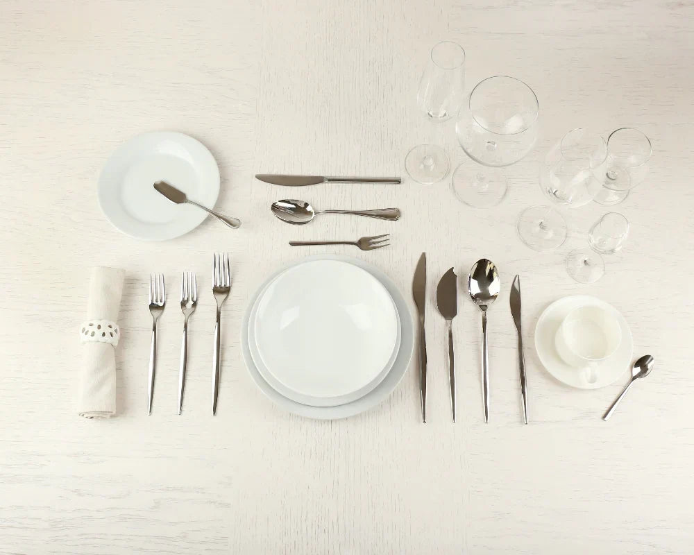 Formal place setting showing the correct napkin placement to the left of the dinner plate with complete silverware arrangement.