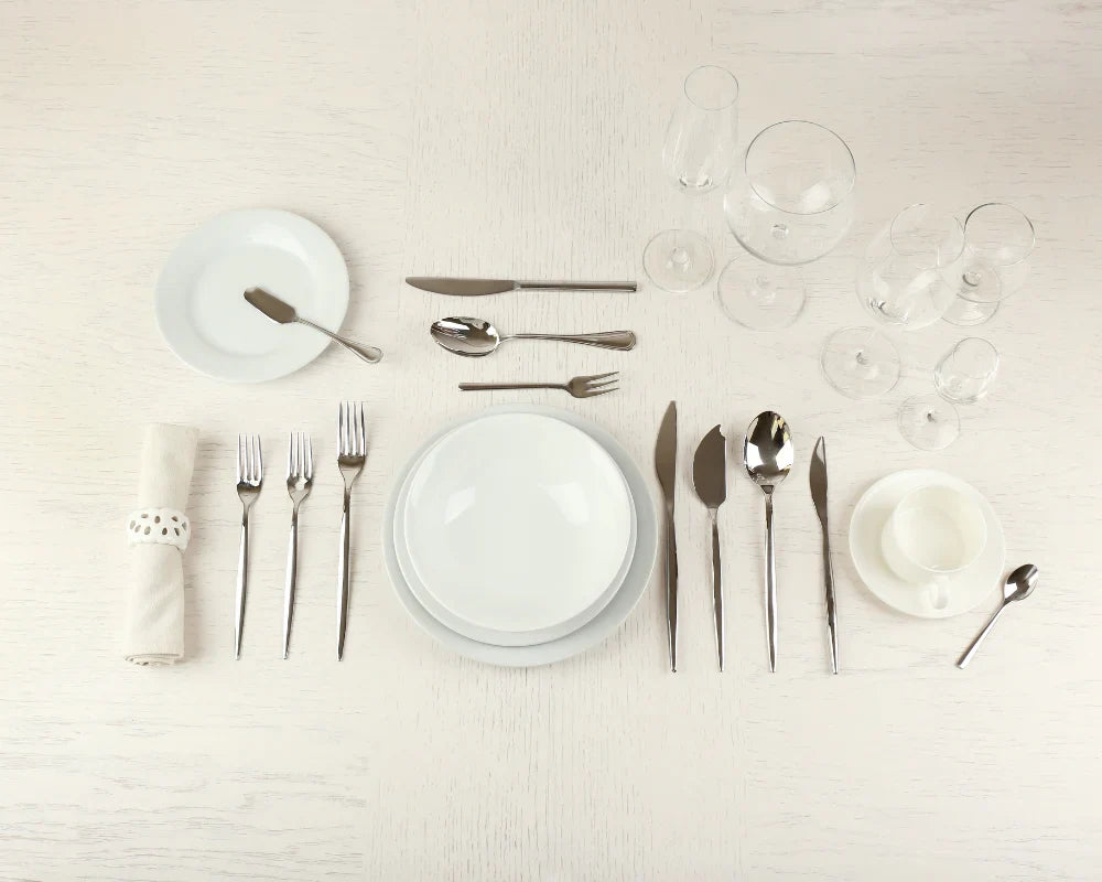 Formal place setting showing the correct napkin placement to the left of the dinner plate with complete silverware arrangement.