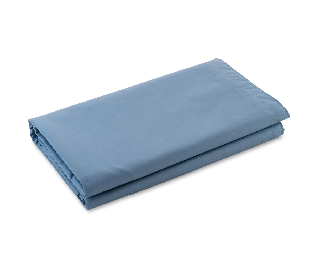 Light blue cotton sateen flat sheet neatly spread on a King size bed

