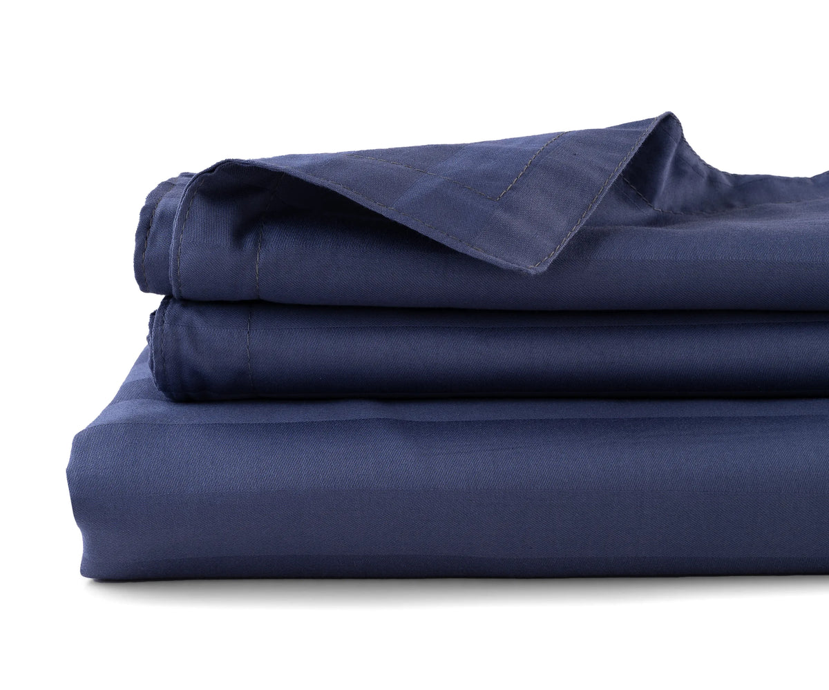 Striped cotton sateen flat sheet neatly spread on a bed in elegant pattern
