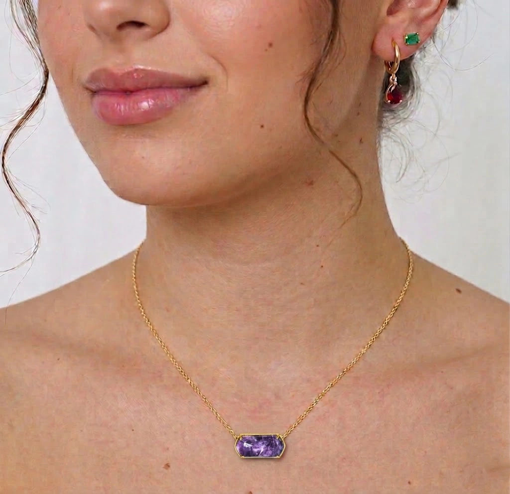 Make a statement with this charoite stone necklace, featuring a unique purple gemstone set in a gold chain for a bold yet elegant look.