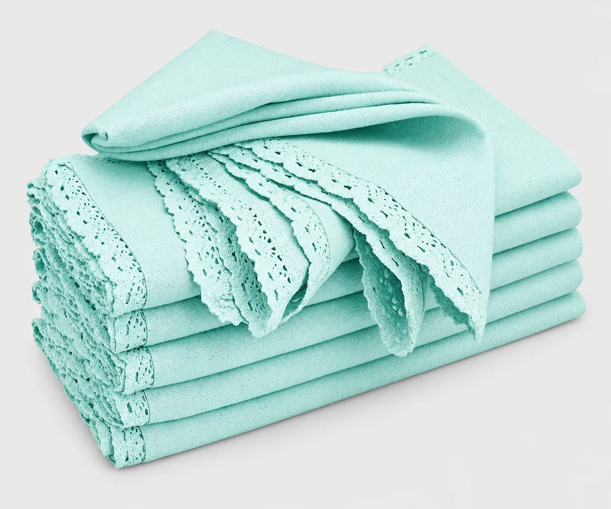 A stack of folded baby blue cotton cloth napkins featuring delicate lace trim and cutwork edges