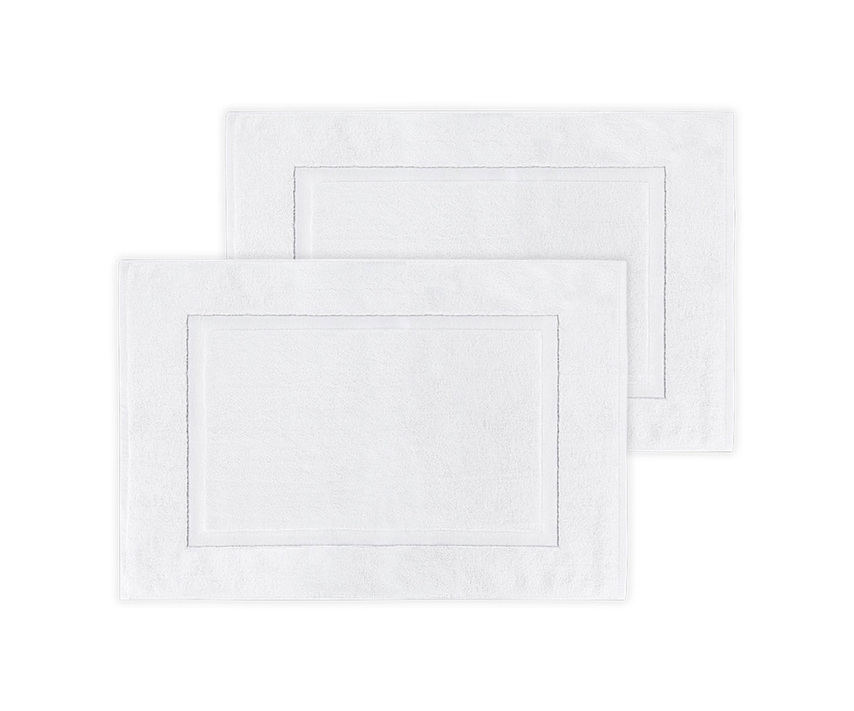 Two white bath mats with a subtle pattern on a white background
