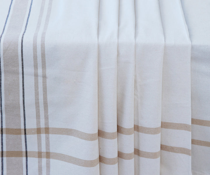 Elegant French tablecloth with white and brown stripes laid out on a table
