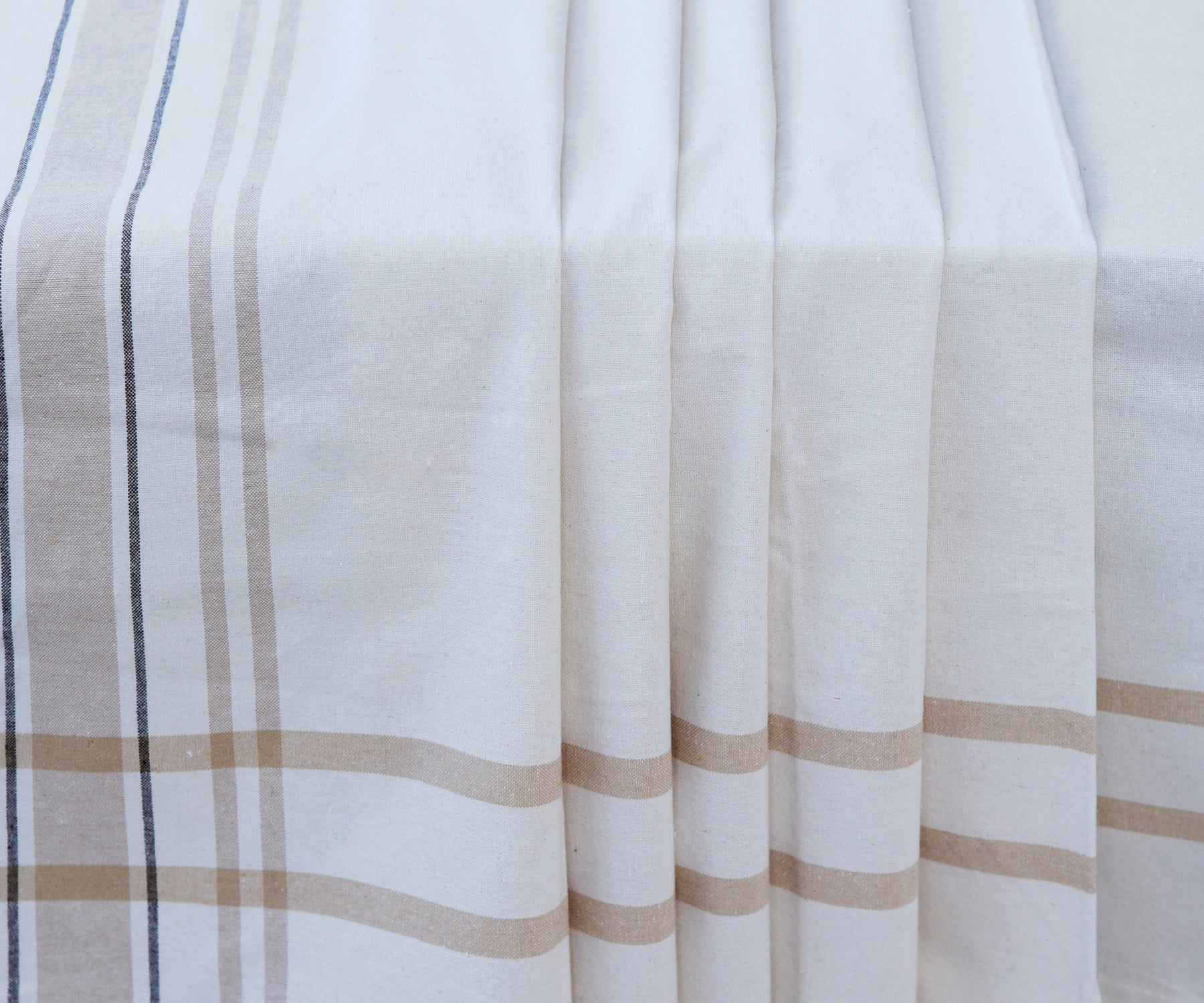 Elegant French tablecloth with white and brown stripes laid out on a table