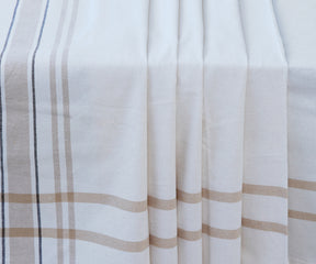Elegant French tablecloth with white and brown stripes laid out on a table