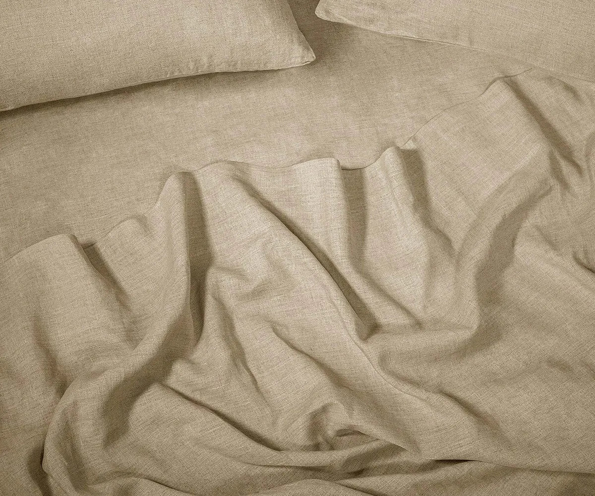 Beige linen sheet set made from 100% stonewashed linen, displayed on a neatly made bed in a minimalist bedroom setting.