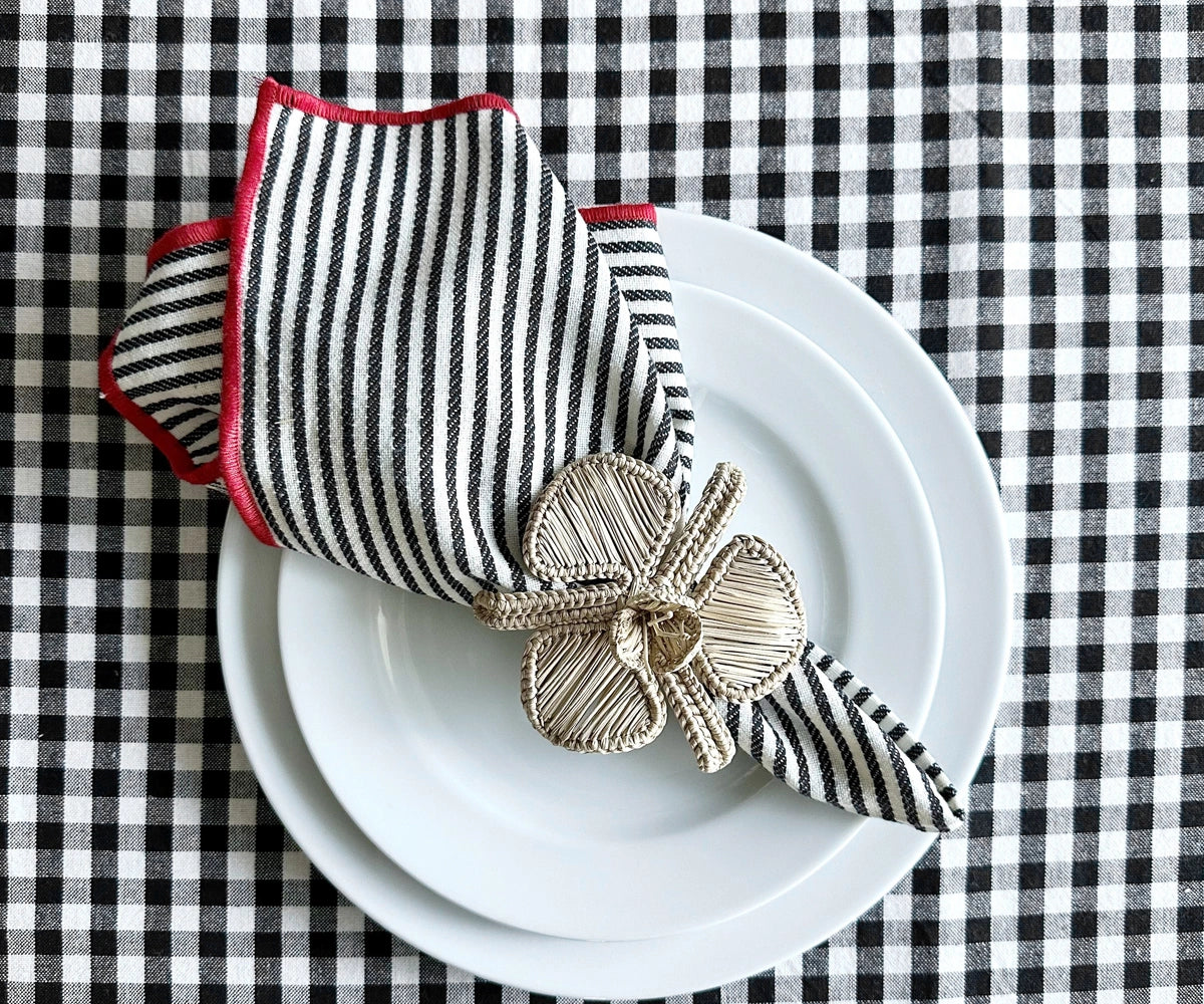 Elegant dining table setup featuring black striped napkins with red borders and white plates.