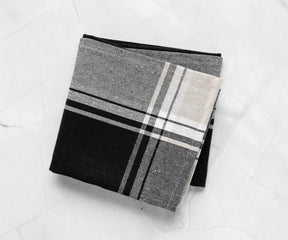 "A vibrant black and white kitchen towel spread across a dining table.