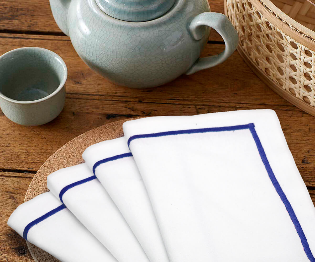 Dining table set with four white dinner napkins and a teapot