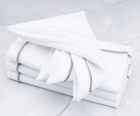 Stack of white dinner napkins with silver trims
