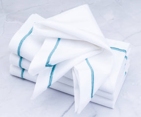 Pile of white dinner napkins with blue stripes