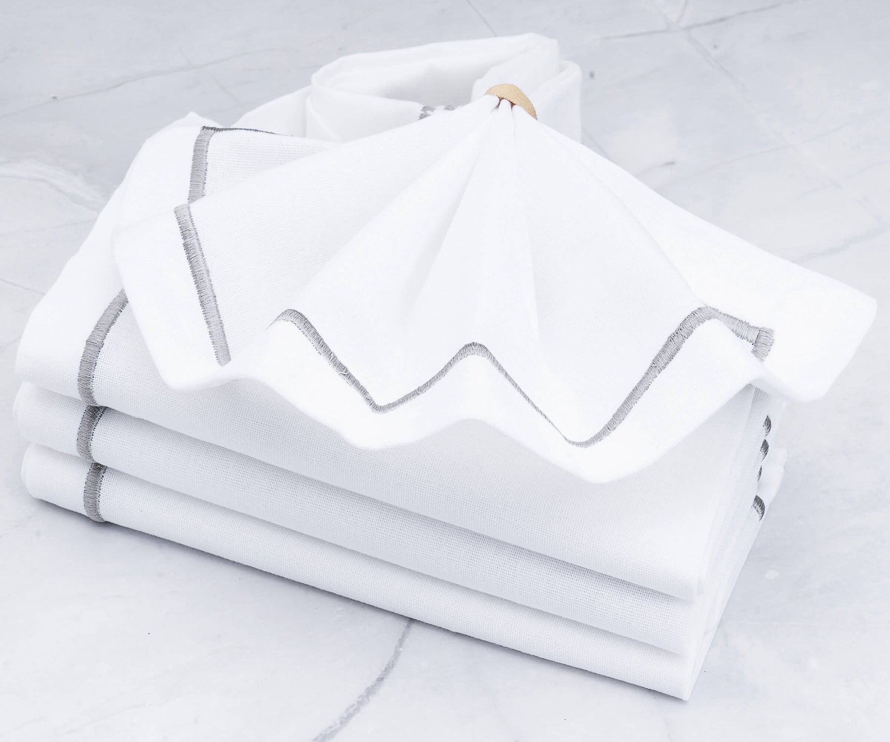Pile of white dinner napkins with one folded on top