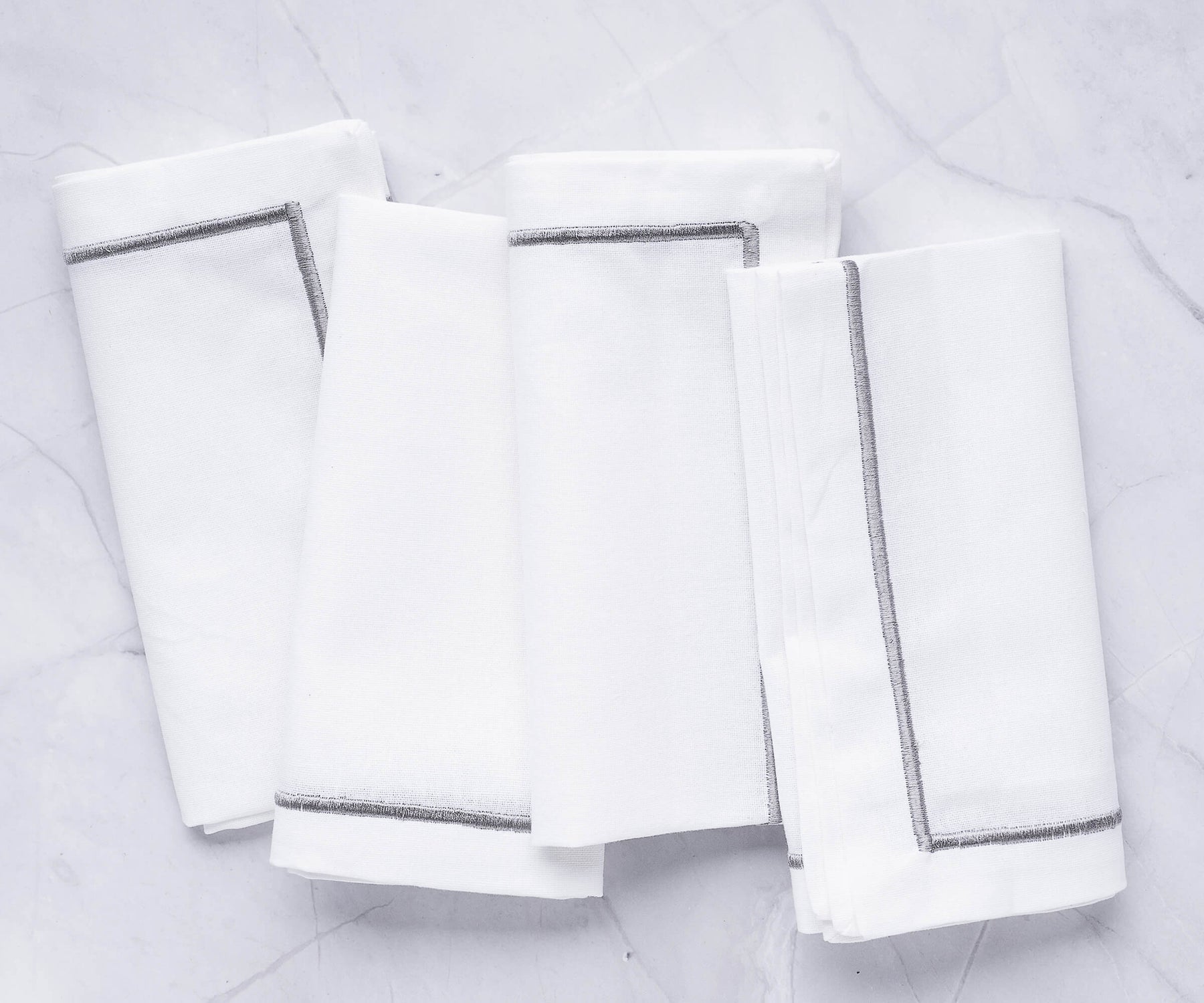 Set of four white dinner napkins with black trim