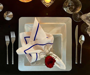 White dinner napkin styled with a rose at a place setting