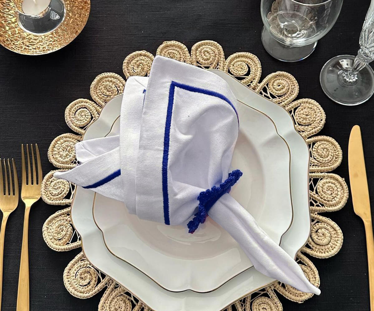 White dinner napkin styled with a rose at a place setting