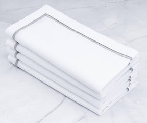 Four neatly folded white dinner napkins stacked on each other