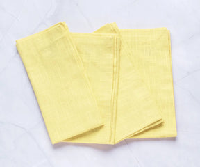 Butter yellow cotton napkins neatly folded in a stack – 100% cotton reusable cloth napkins, perfect for summer dining.