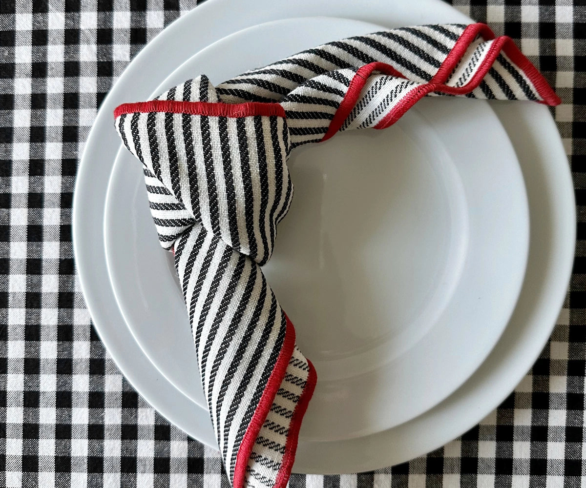 black striped napkin with red trim placed on a dinner plate for an elegant look.