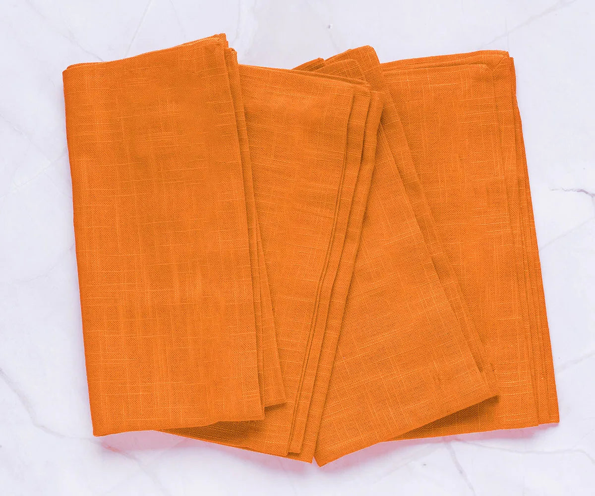 Set of 12 Clementine Orange cotton napkins neatly folded on a summer table, made from 100% cotton – perfect for vibrant seasonal dining.