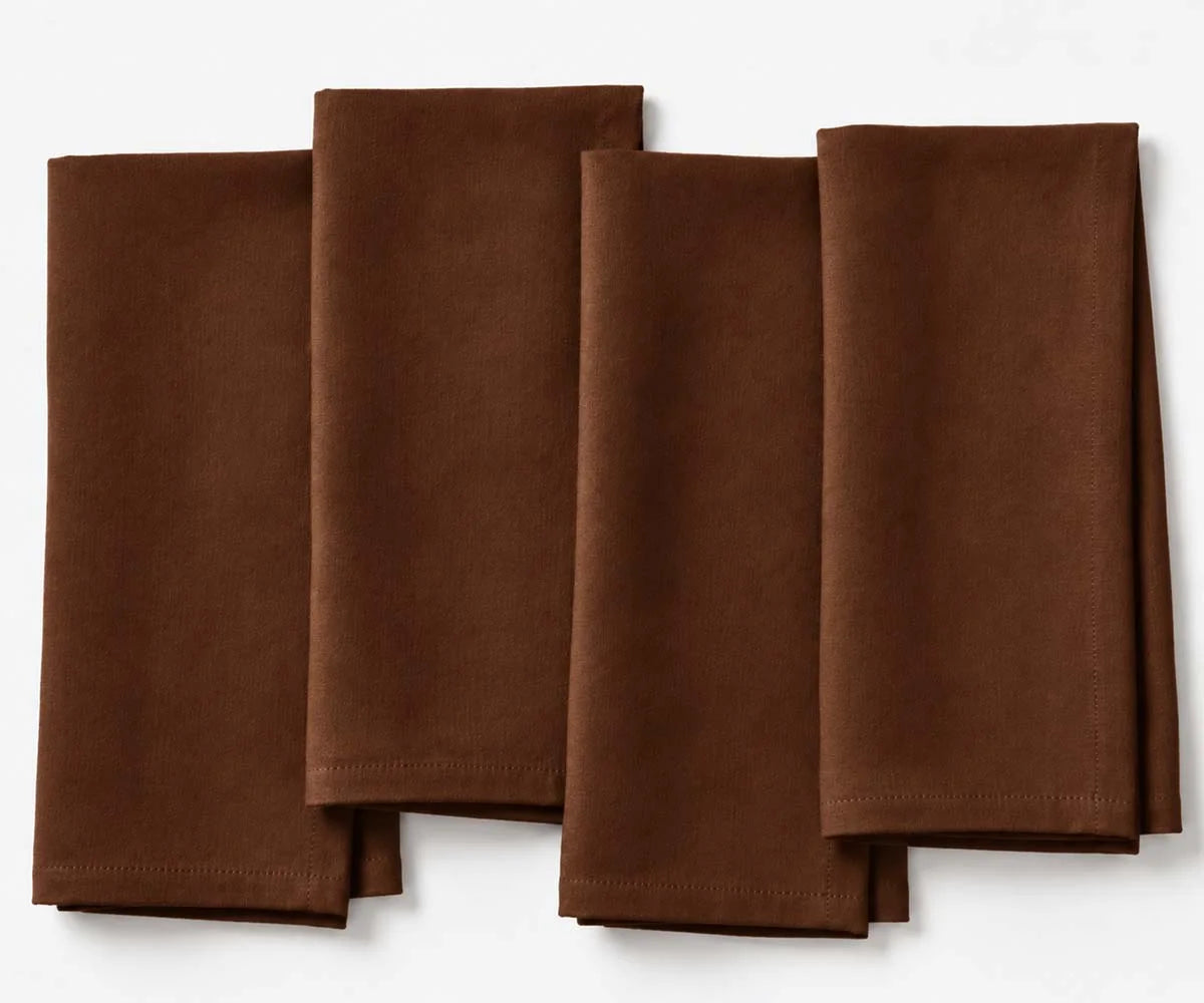 Set of four folded coffee brown linen cloth dinner napkins arranged side by side