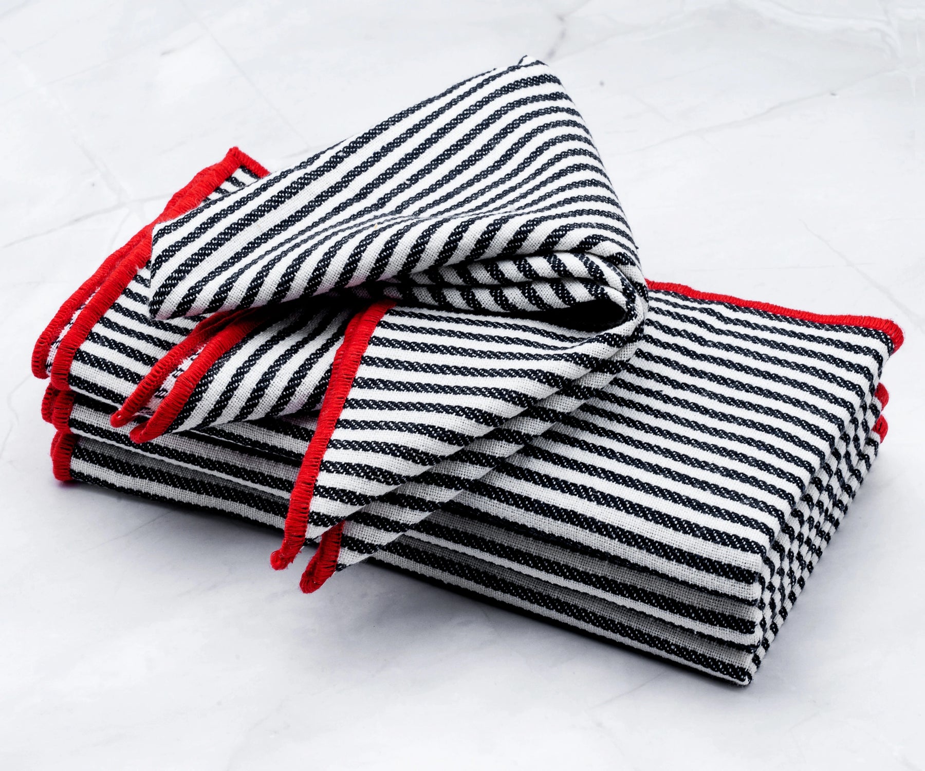 Black striped cotton napkins with red borders arranged for a dinner party table setting.