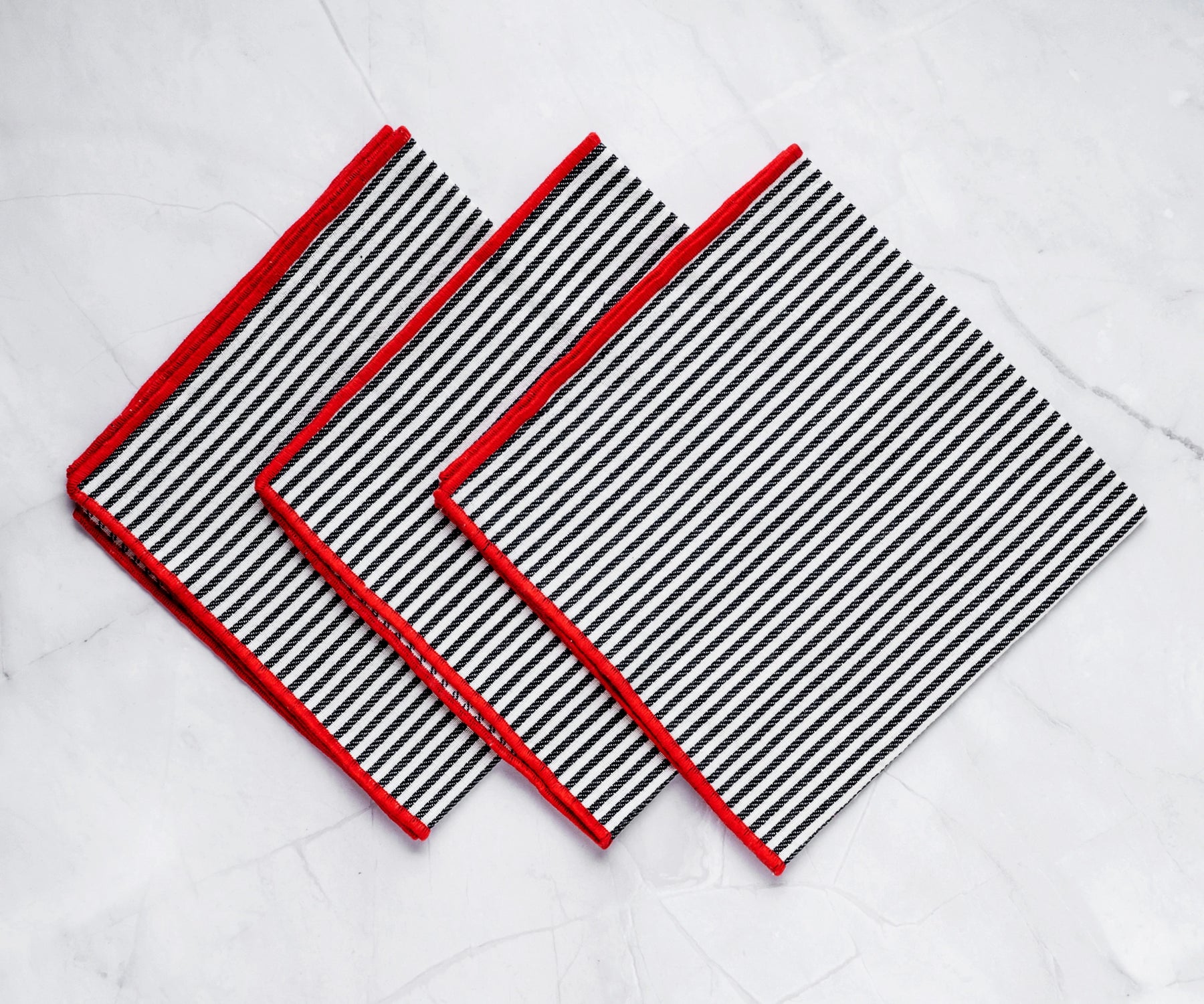 Rolled black striped napkin with red trim placed on a dinner plate for an elegant look.