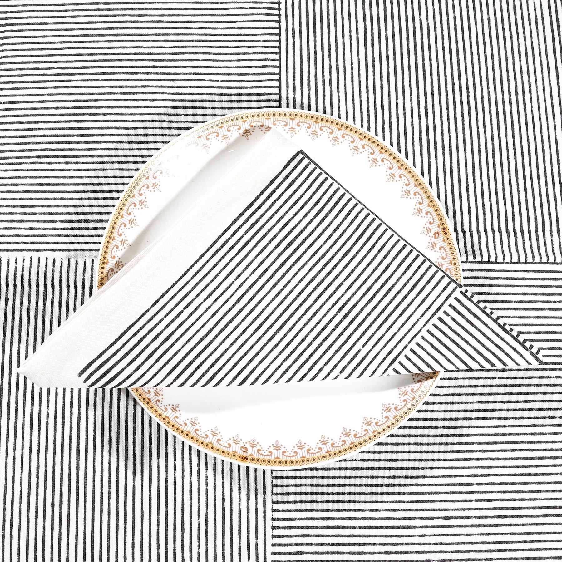 Set of 4 black block printed cotton napkins with striped line design, neatly folded on a dining table