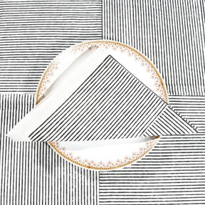 Set of 4 black block printed cotton napkins with striped line design, neatly folded on a dining table
