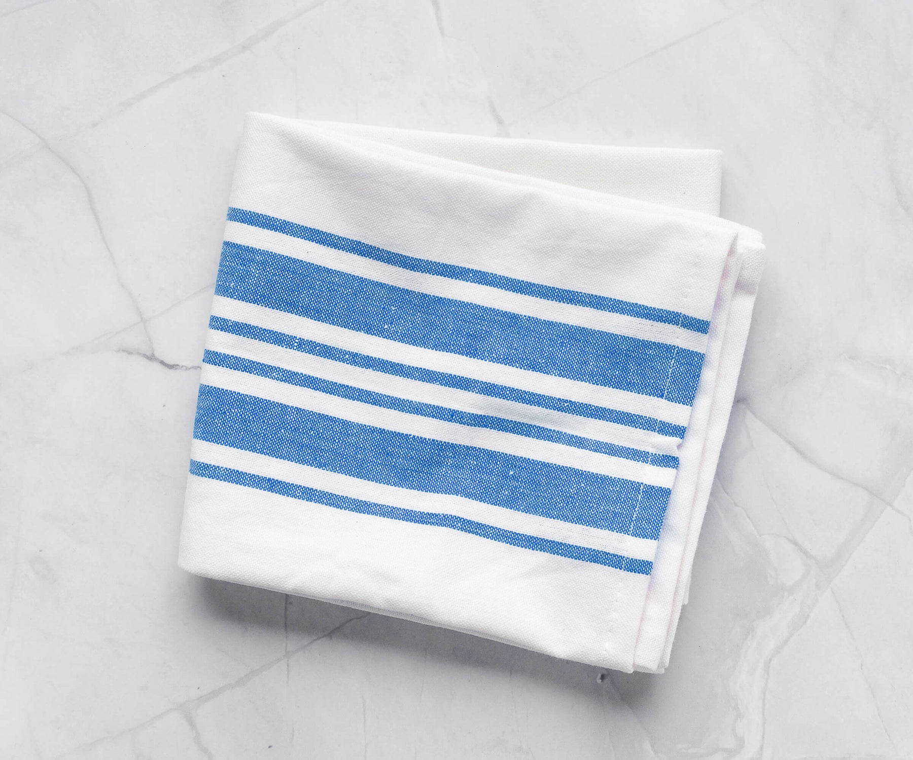 Kitchen towel with blue stripes against a marble background