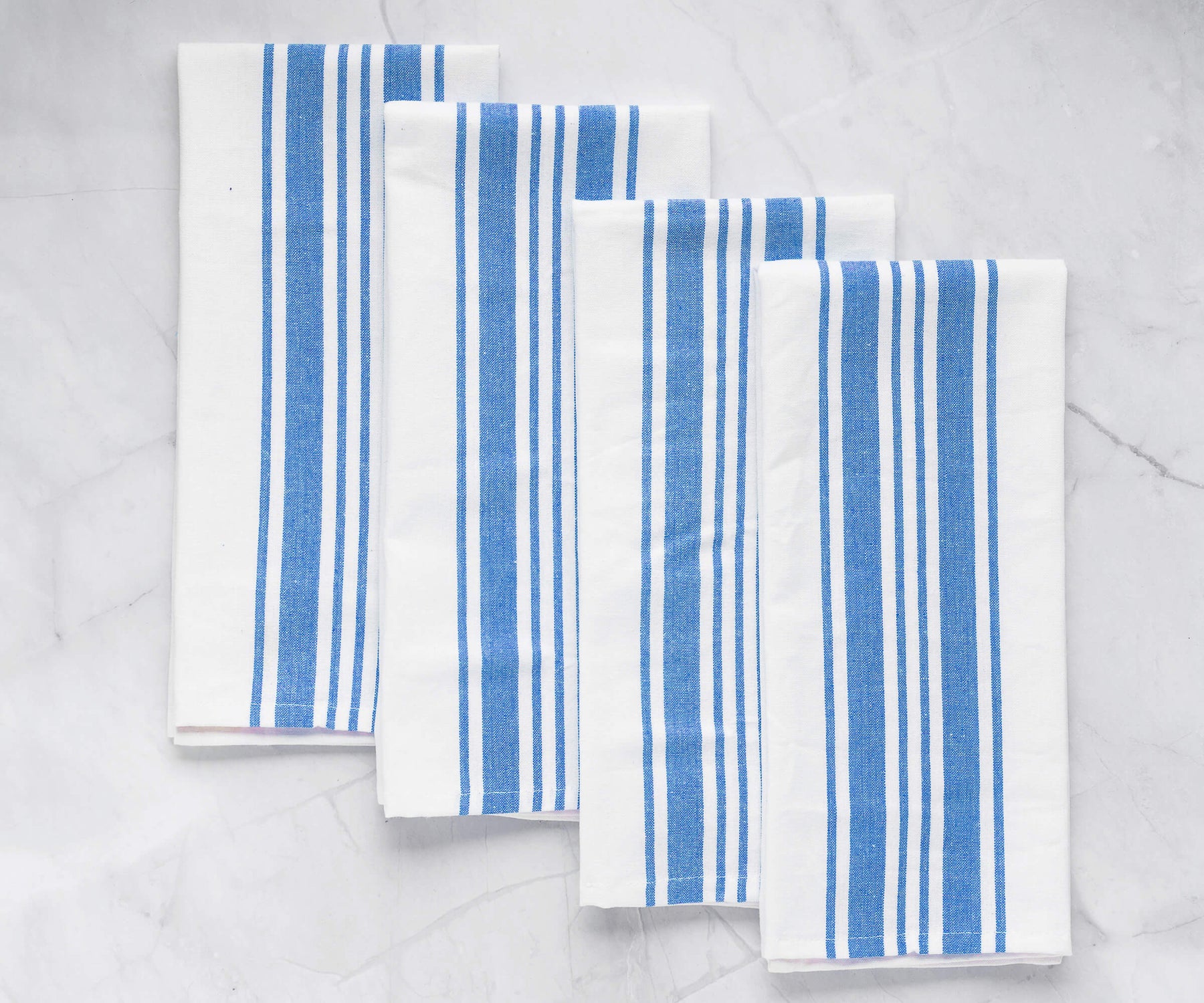 Blue and white striped kitchen cloths arranged on a marble surface