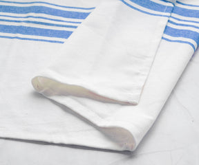 A white kitchen towel with blue stripes casually draped over a marble surface