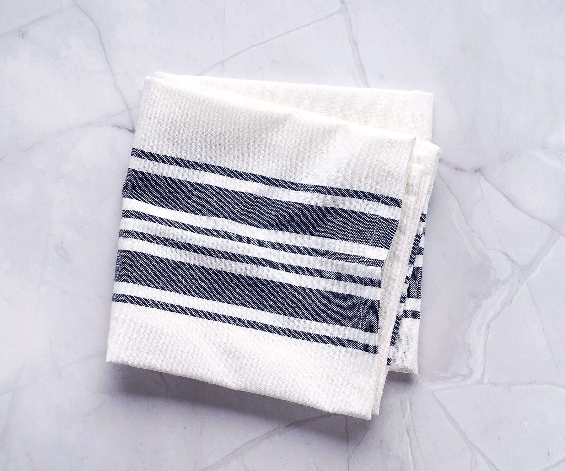 Black and white striped kitchen towel draped over a marble countertop