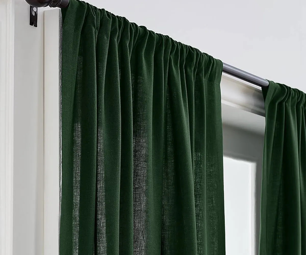 Green linen curtains draped in a bright living room, allowing natural light to filter through.