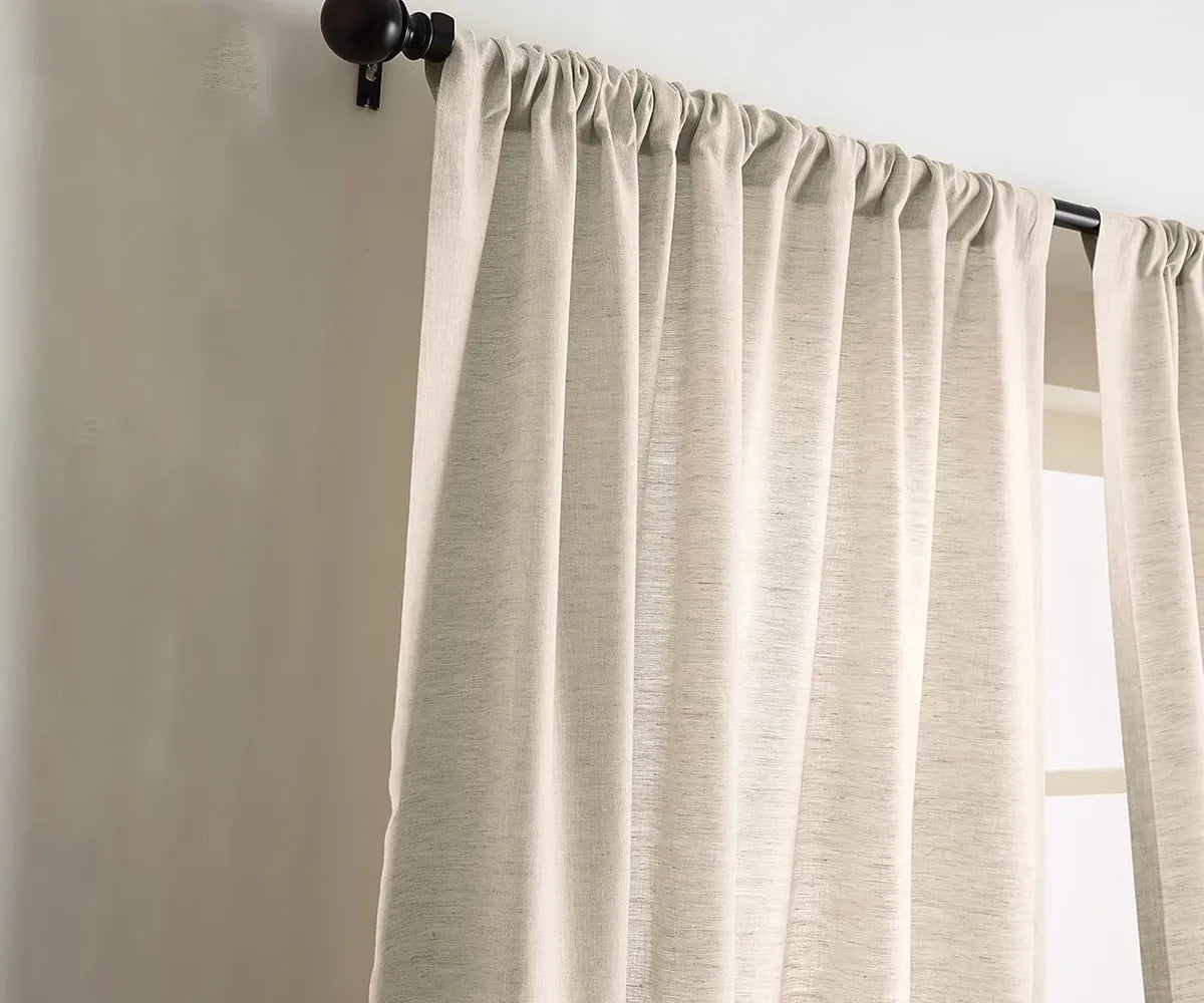 Natural linen curtains hanging in a sunlit room, creating a calm and airy atmosphere.