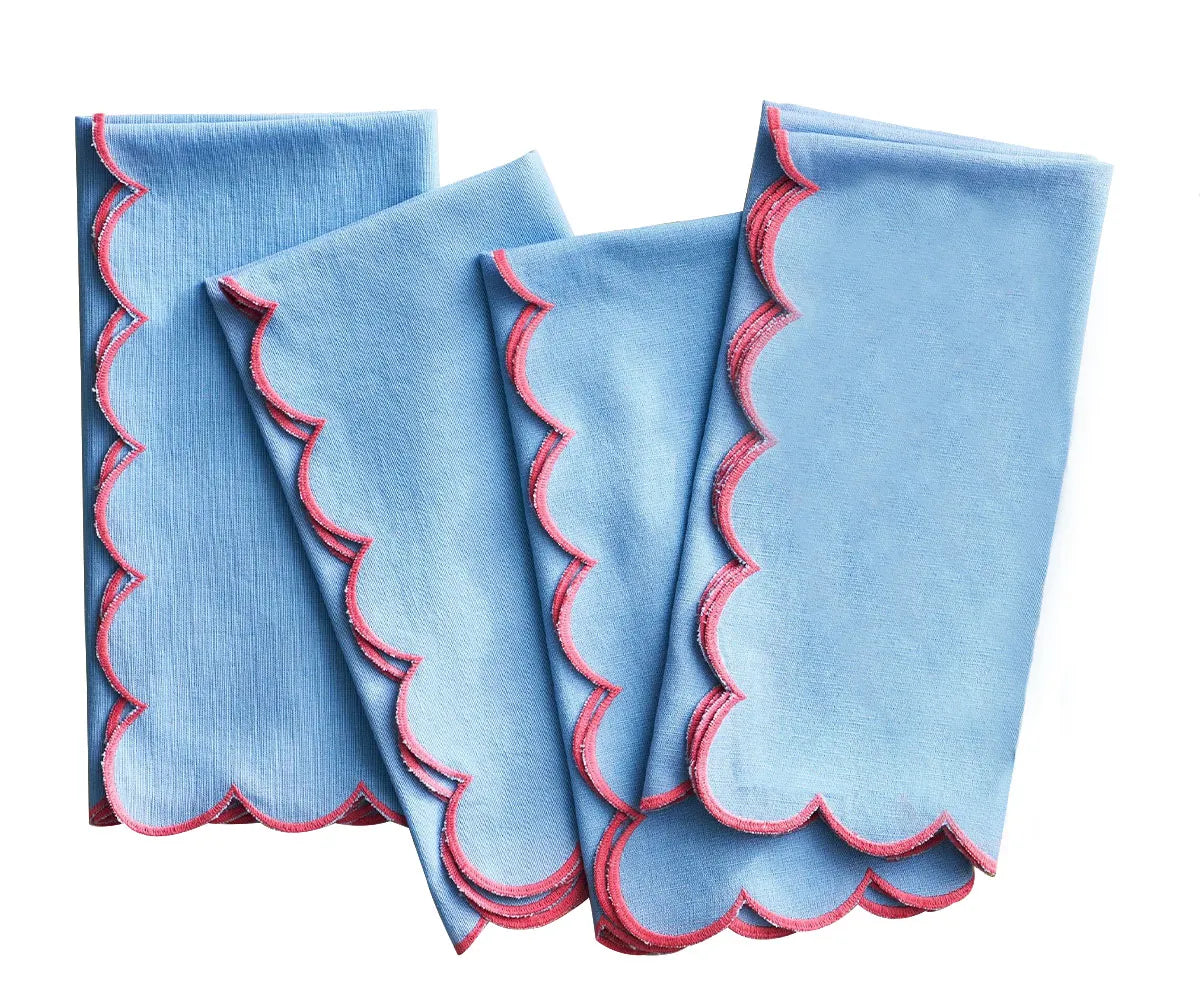 Blue scalloped edge cotton dinner napkins neatly folded on a dining table with matching placemats – set of 12