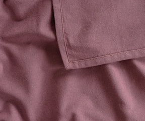Dusty red rectangular cotton tablecloth covering an outdoor dining table, adding a warm and classic touch to picnics, family cookouts, or garden parties.