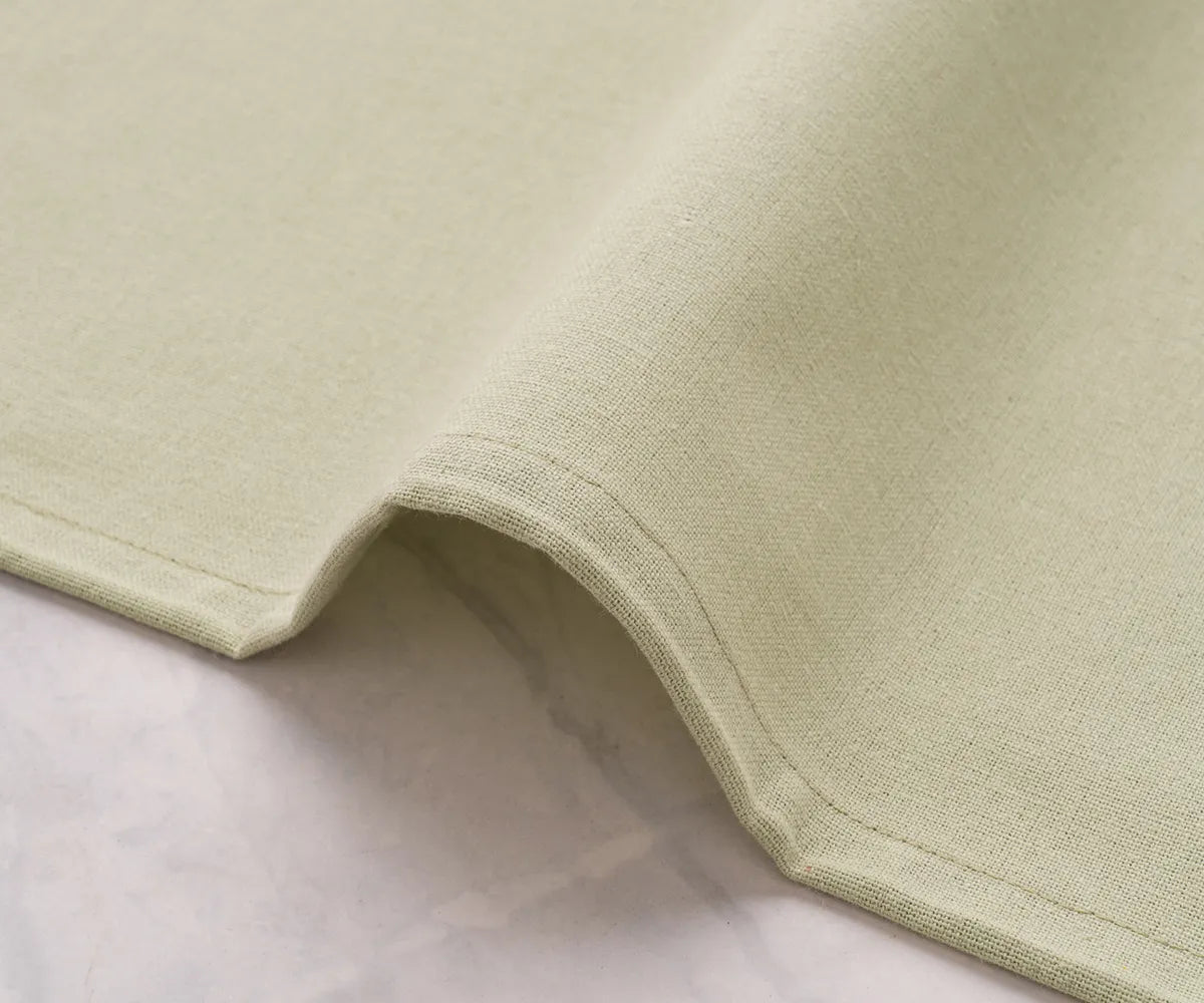 Soft sage green cotton napkins placed on a farmhouse dining table with earthy accents, ideal for everyday meals and seasonal gatherings