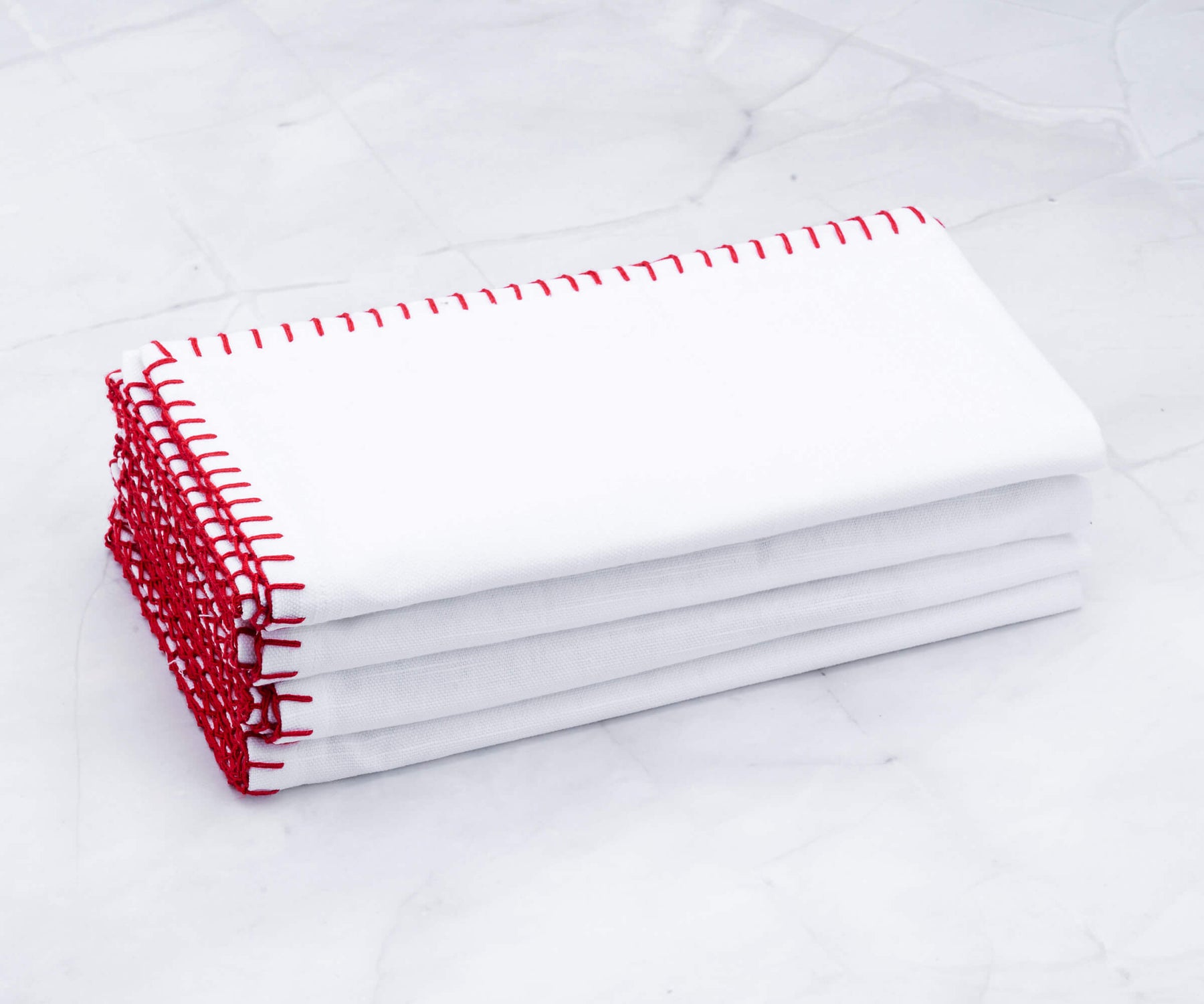 Pile of shell edge wedding napkins with decorative red stitching