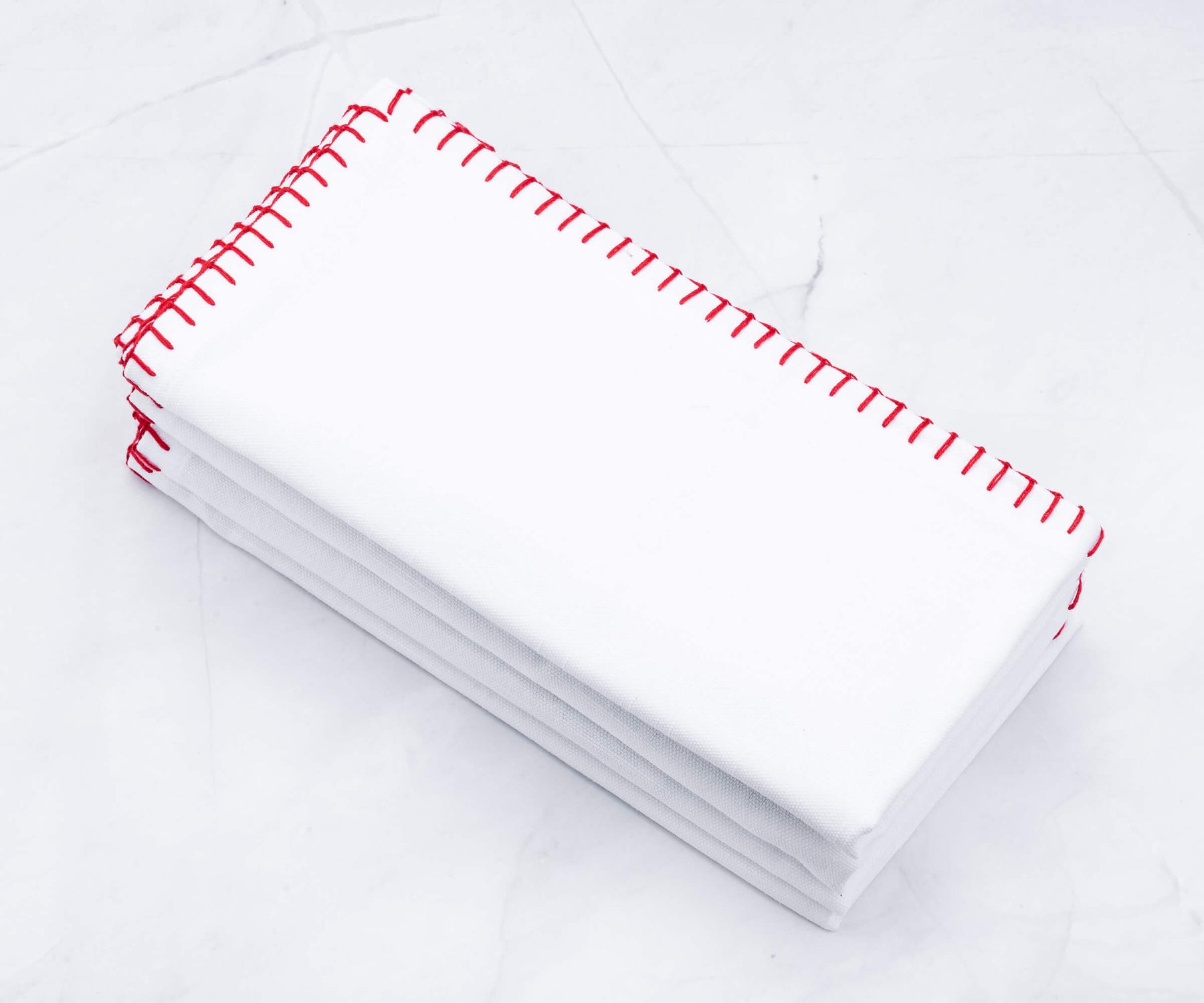 Bunch of white wedding napkins with red shell stitching stacked neatly