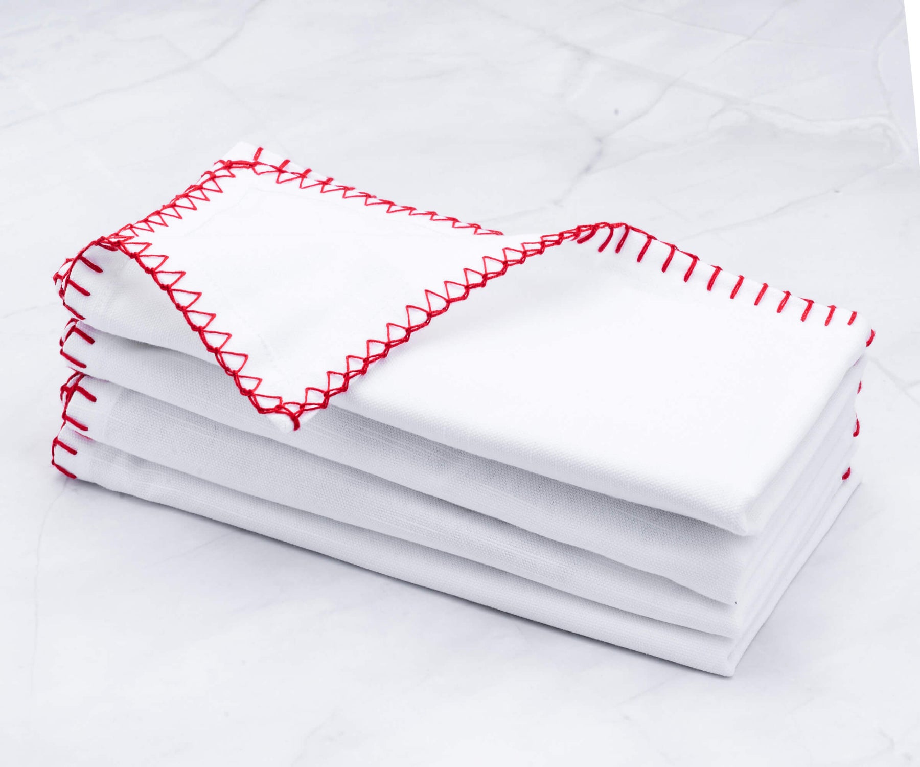 Neat stack of shell edge napkins with vibrant red embroidery