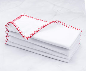 Neat stack of shell edge napkins with vibrant red embroidery